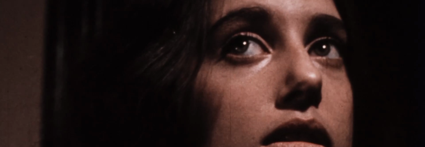 Close up of the face of a young woman with light skin tone and dark hair in shadows