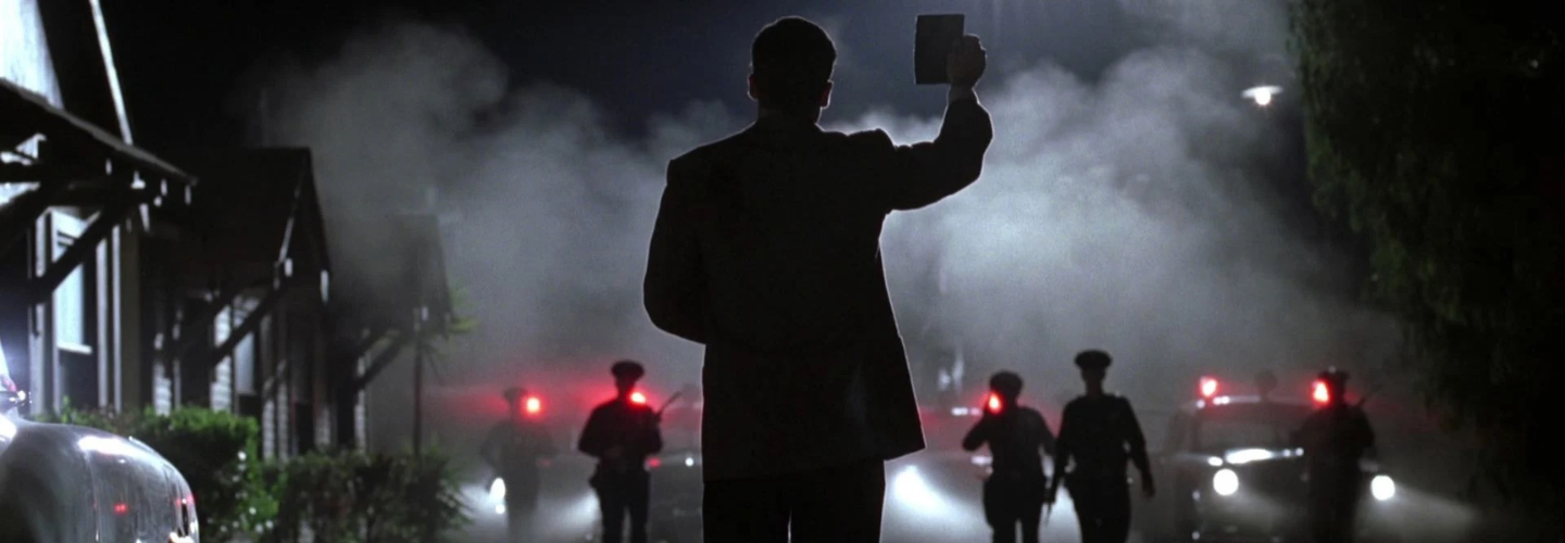 silhouetted man holds up ID in front of row of cop cars
