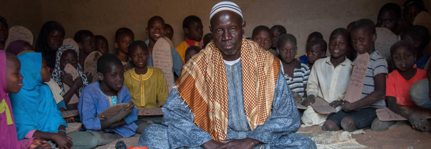 man sitting surrounded by children
