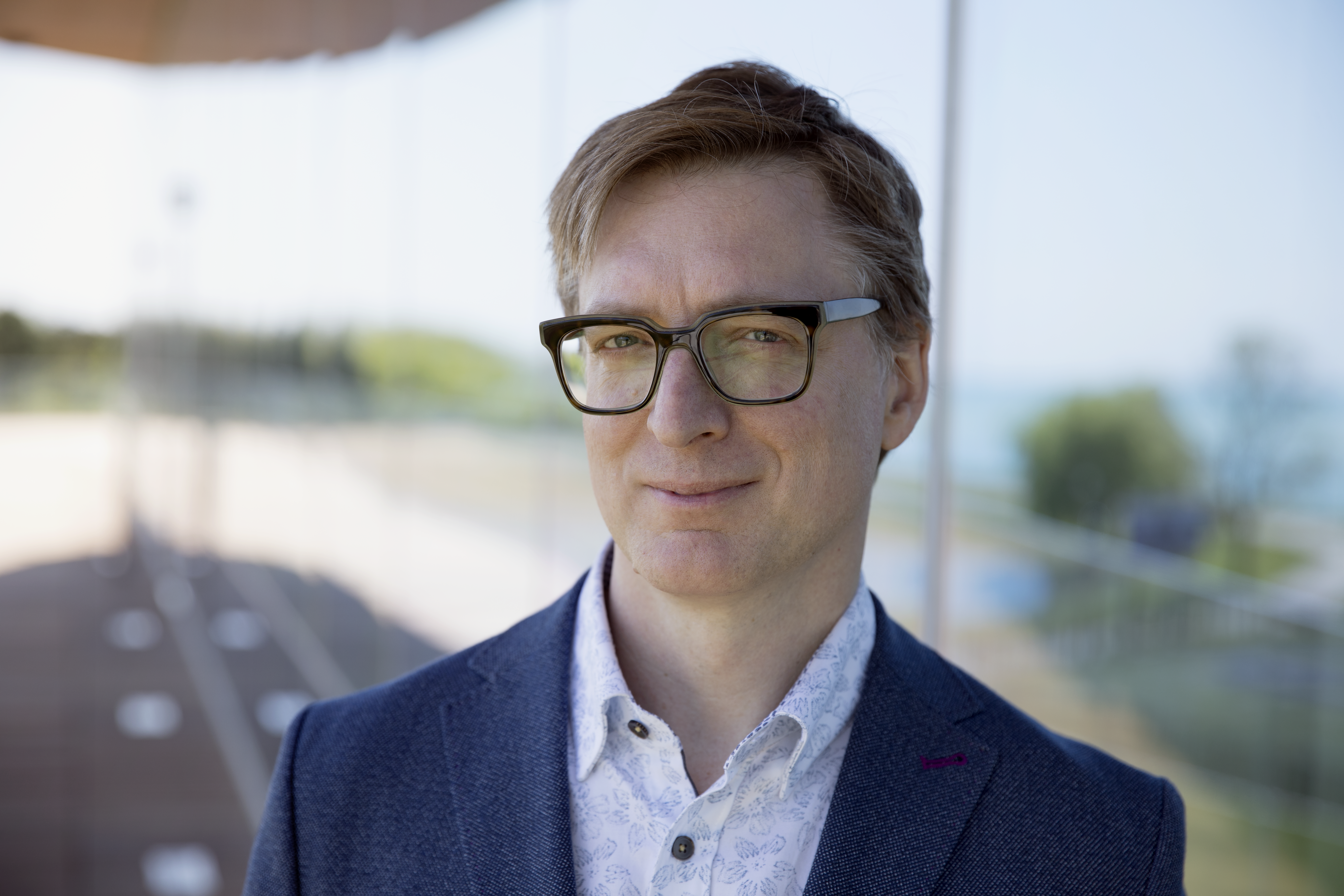 headshot of man in glasses and blue suit