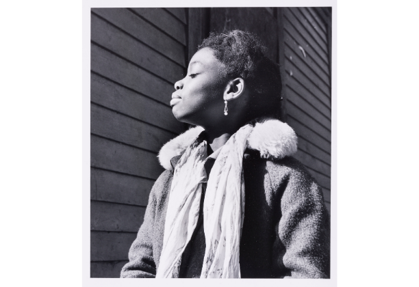 Profile view of a Black girl basking in the sun, her dainty earring in the center of photograph