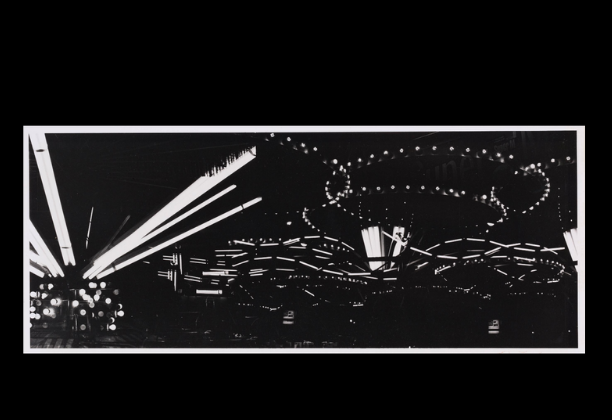 black background with curling shapes of lights from carnival rides