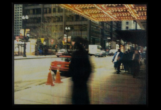 blurred figure stands underneath theater marquee with view of street in background