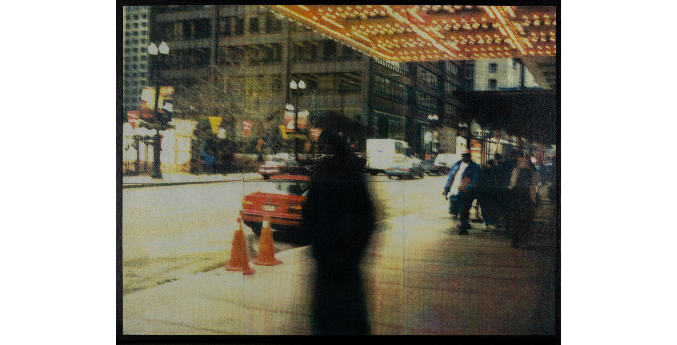 blurred figure stands underneath theater marquee with view of street in background