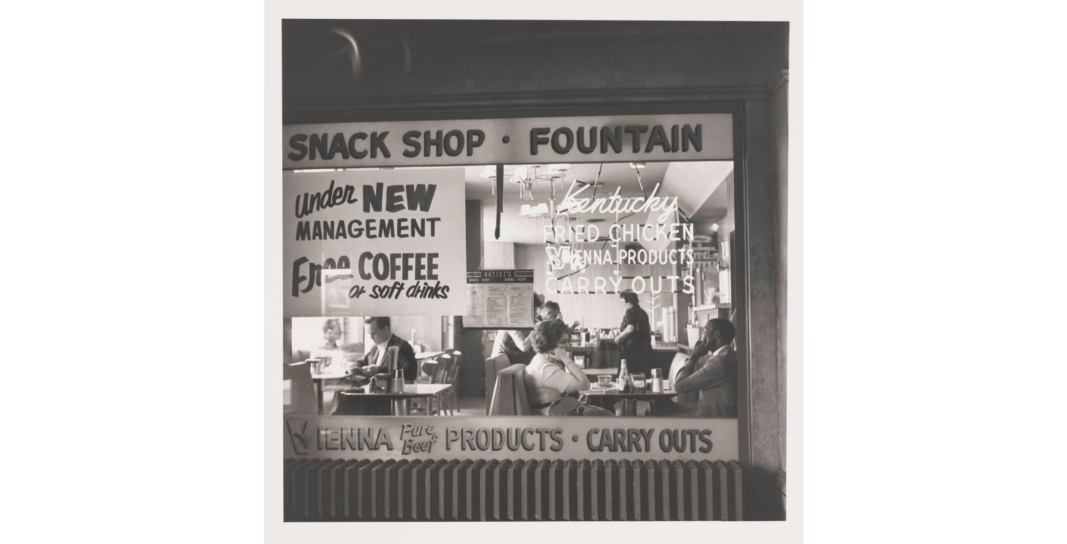 black and white photo of diner window with advertisement text and patrons in booths 