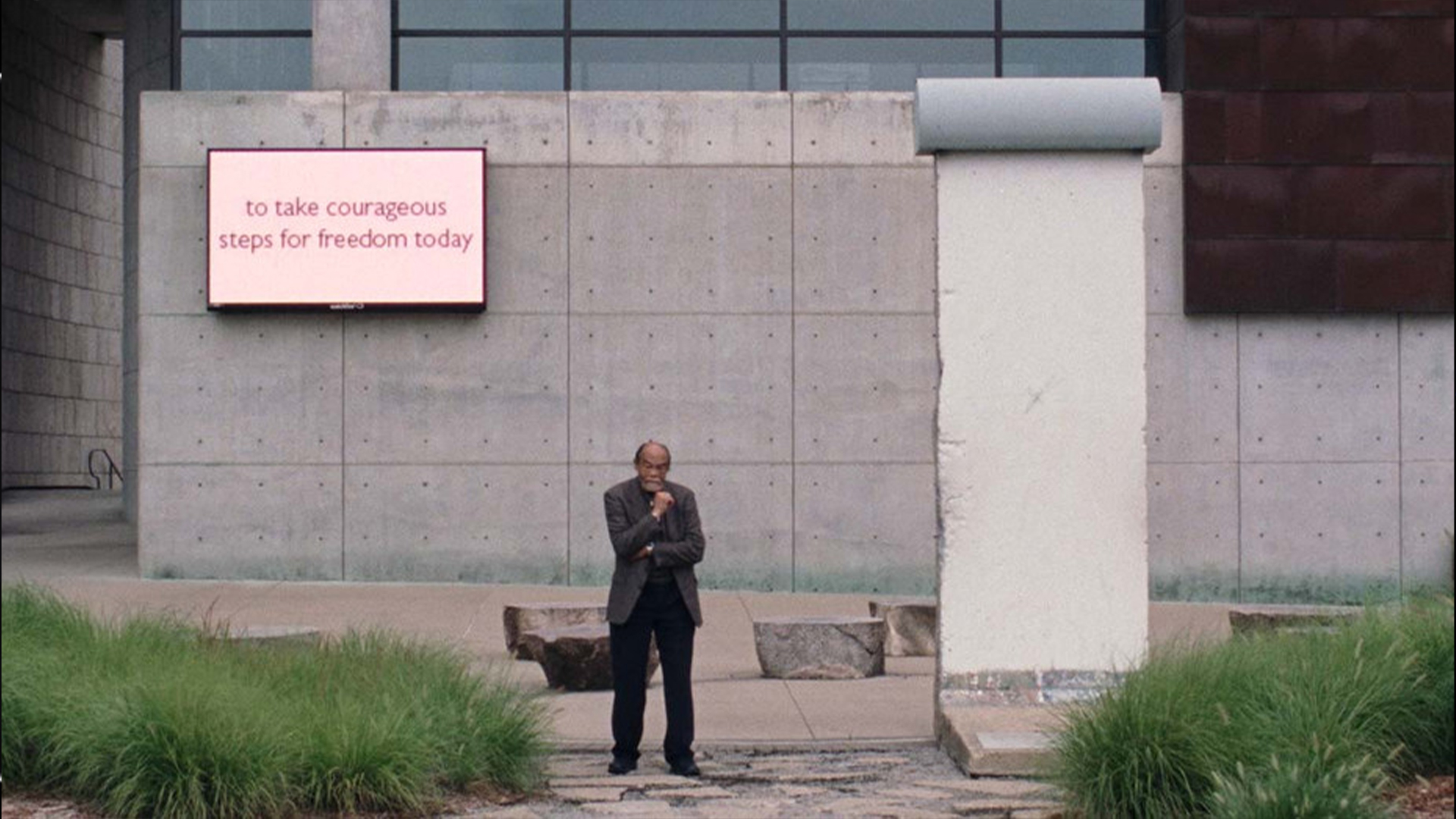 A man stands in front of a fragment of the Berlin wall 