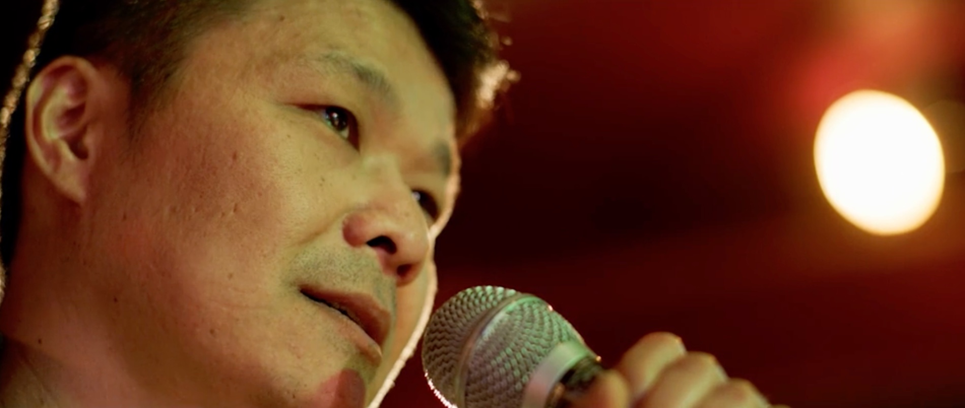 A Hmong man holds a microphone at a Karaoke bar