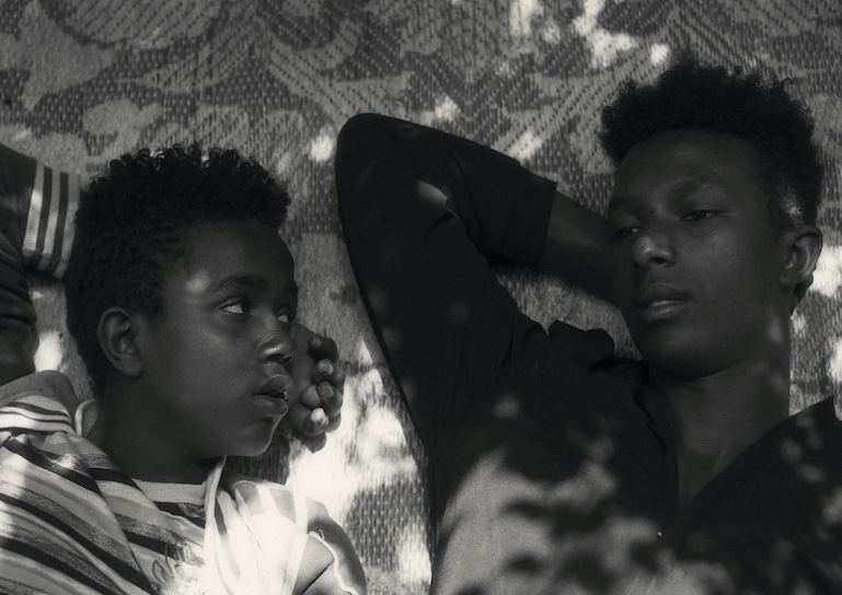 Two young Ethiopian boys lie and talk in the shade.