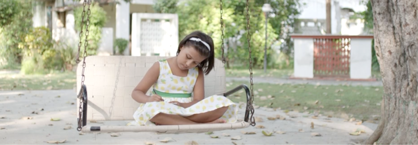 A young girl on a swing with green foliage in the background