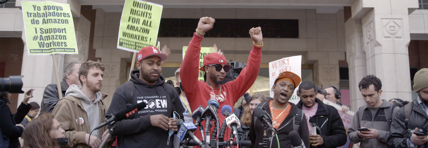 Labor organizers give a press conference. Signs read "Union rights for all Amazon workers!"