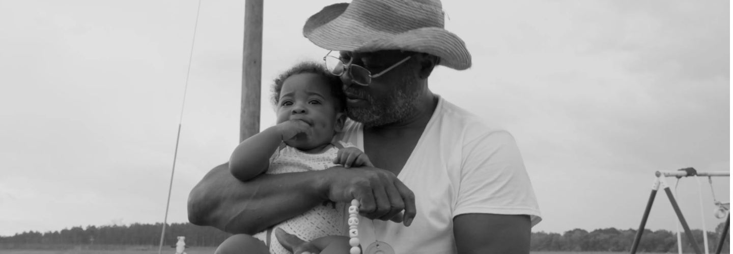 Black and white grandfather holding child