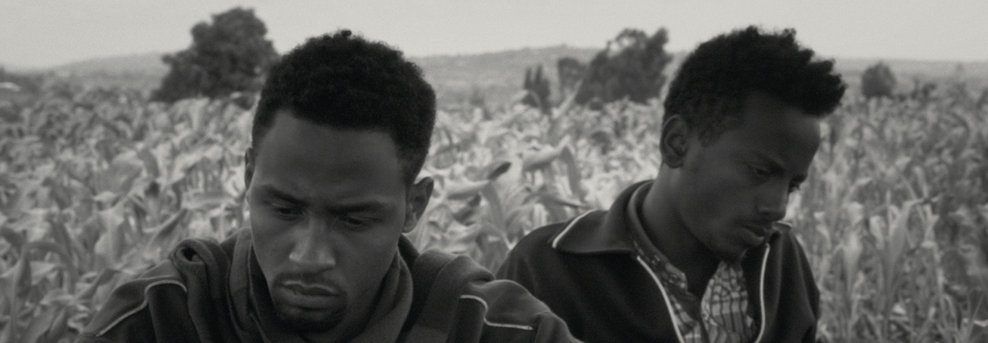 Black and white image of two men up close glancing away from each other