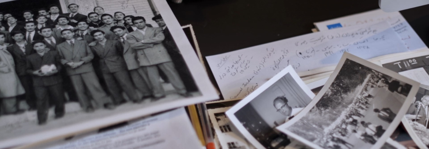 Black and white photos and papers strewn across a desk