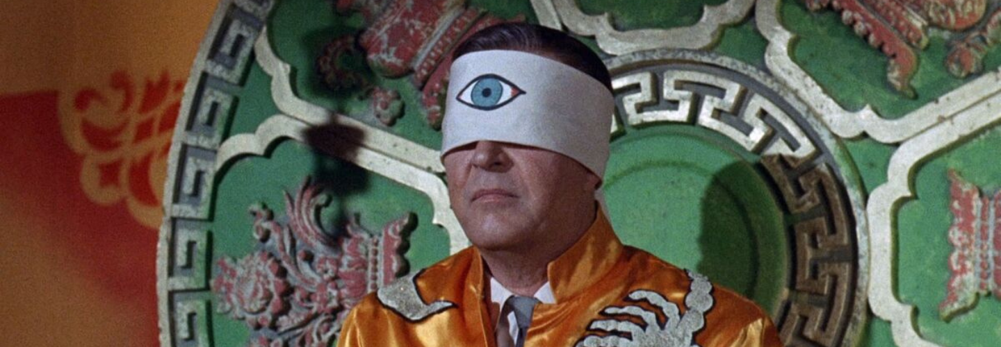 Man wears a blindfold painted with a large eye painted in the center