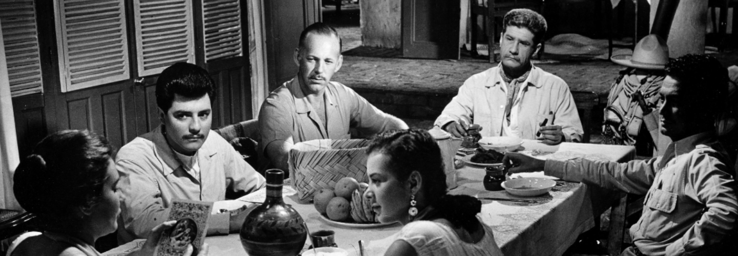 Black and white of a group gathered around a table talking