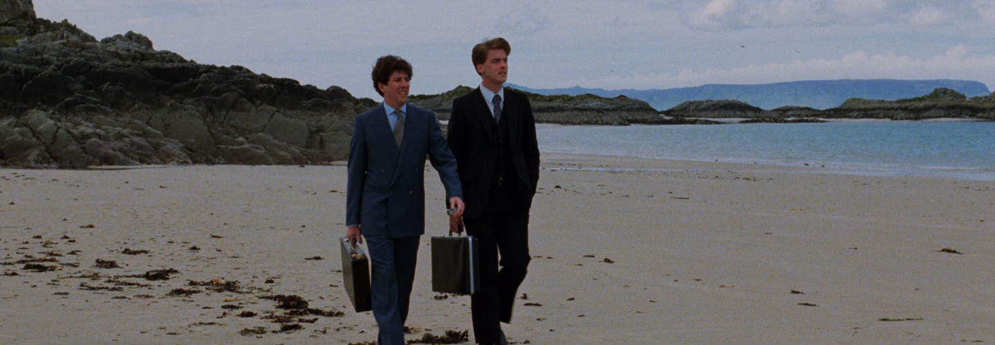 Two men in suits walking on a beach