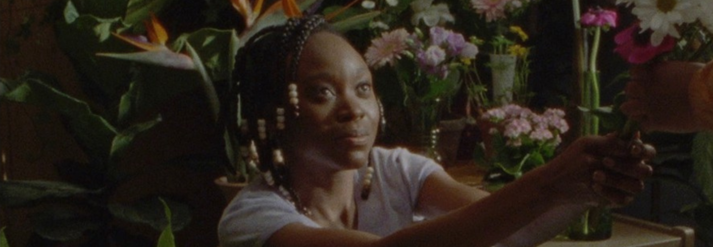 A Black woman with braids surrounded by flowers