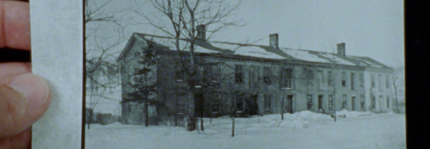 Fingers holding black and white photo of old buildings