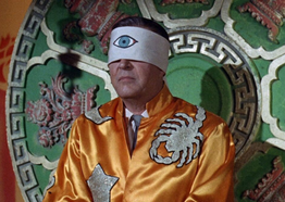 Man wears a blindfold painted with a large eye painted in the center