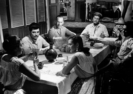Black and white of a group gathered around a table talking