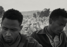 Black and white image of two men up close glancing away from each other