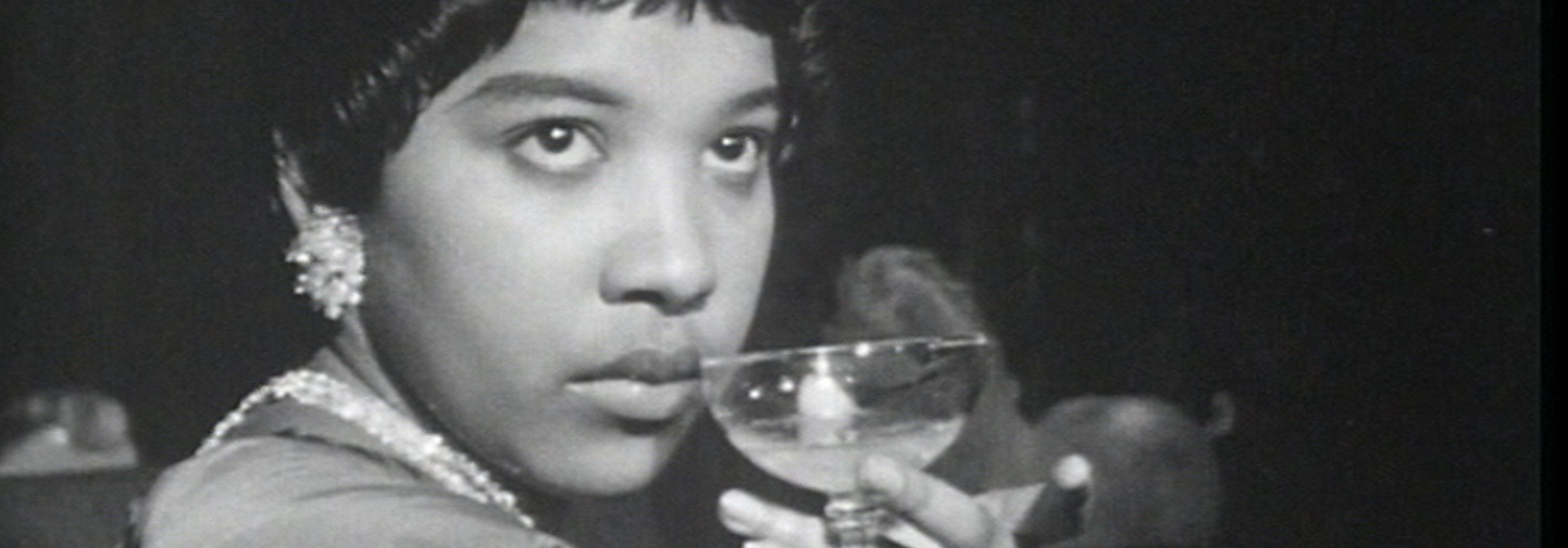 Black and white image of a glamorous African American woman holds a cocktail glass