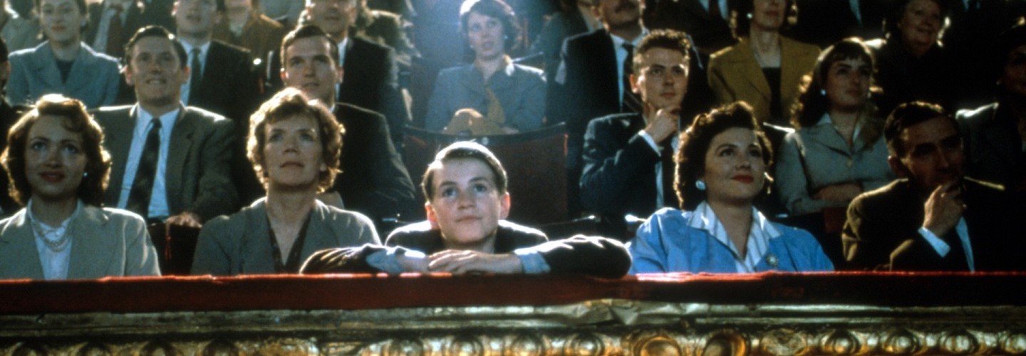 A young boy stares enraptured at the screen in a crowded movie theater
