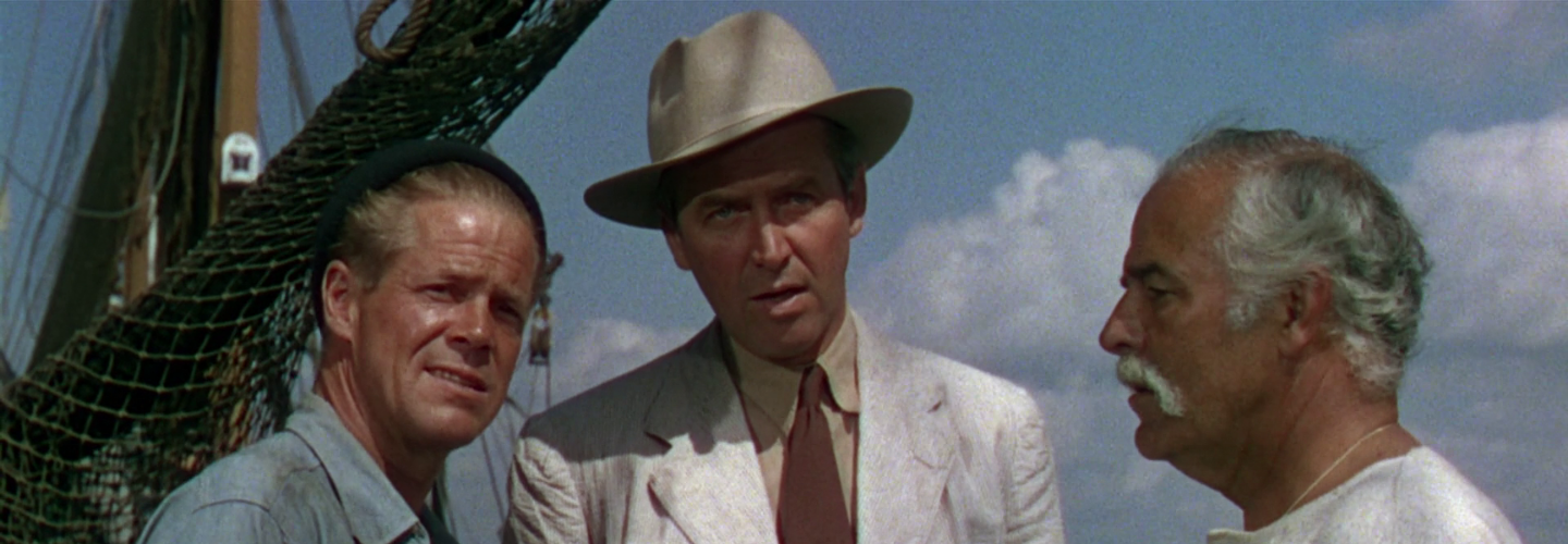 Three men with different styles in conversation with a the mast of a fishing boat behind them