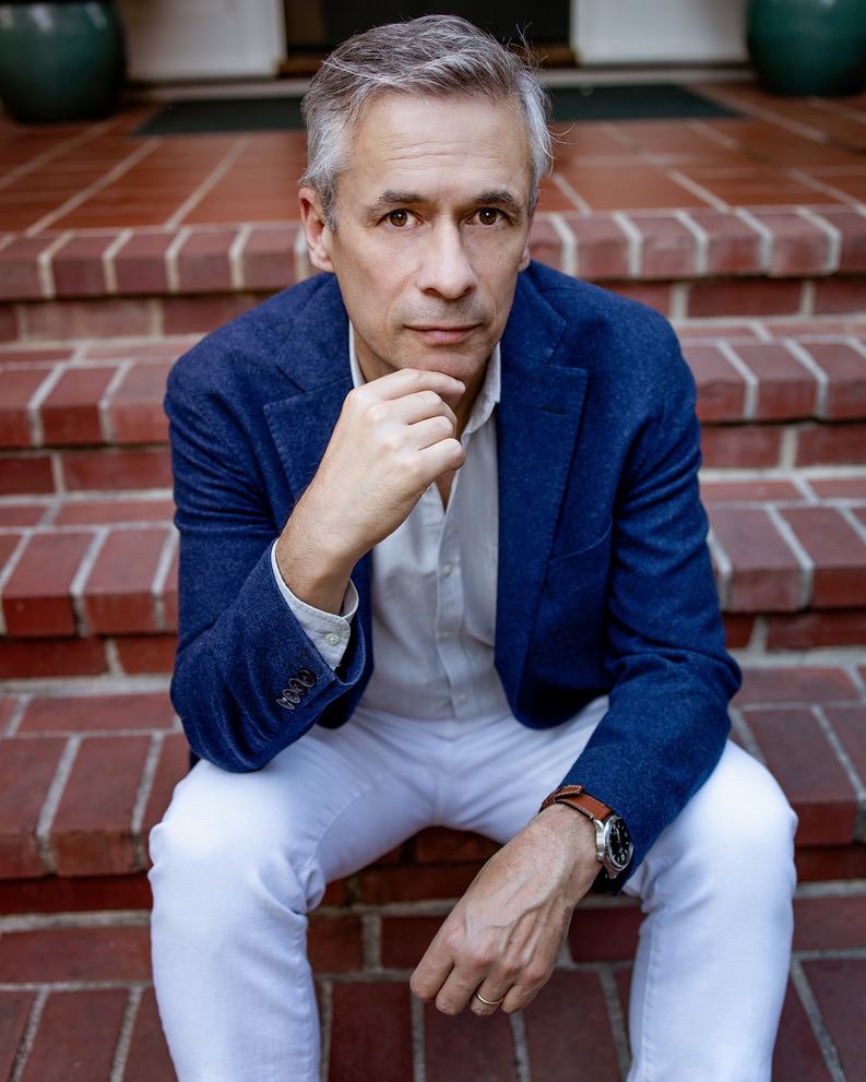 photograph of a white man in a suit sitting on brick steps