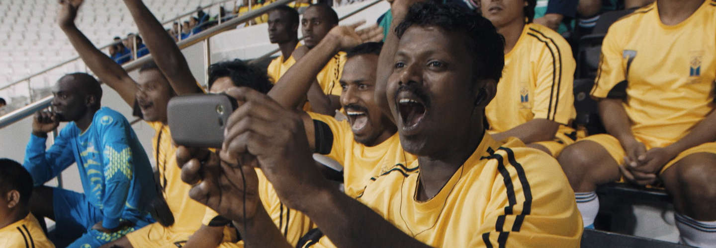 Soccer fans in yellow jerseys scream and applaud 