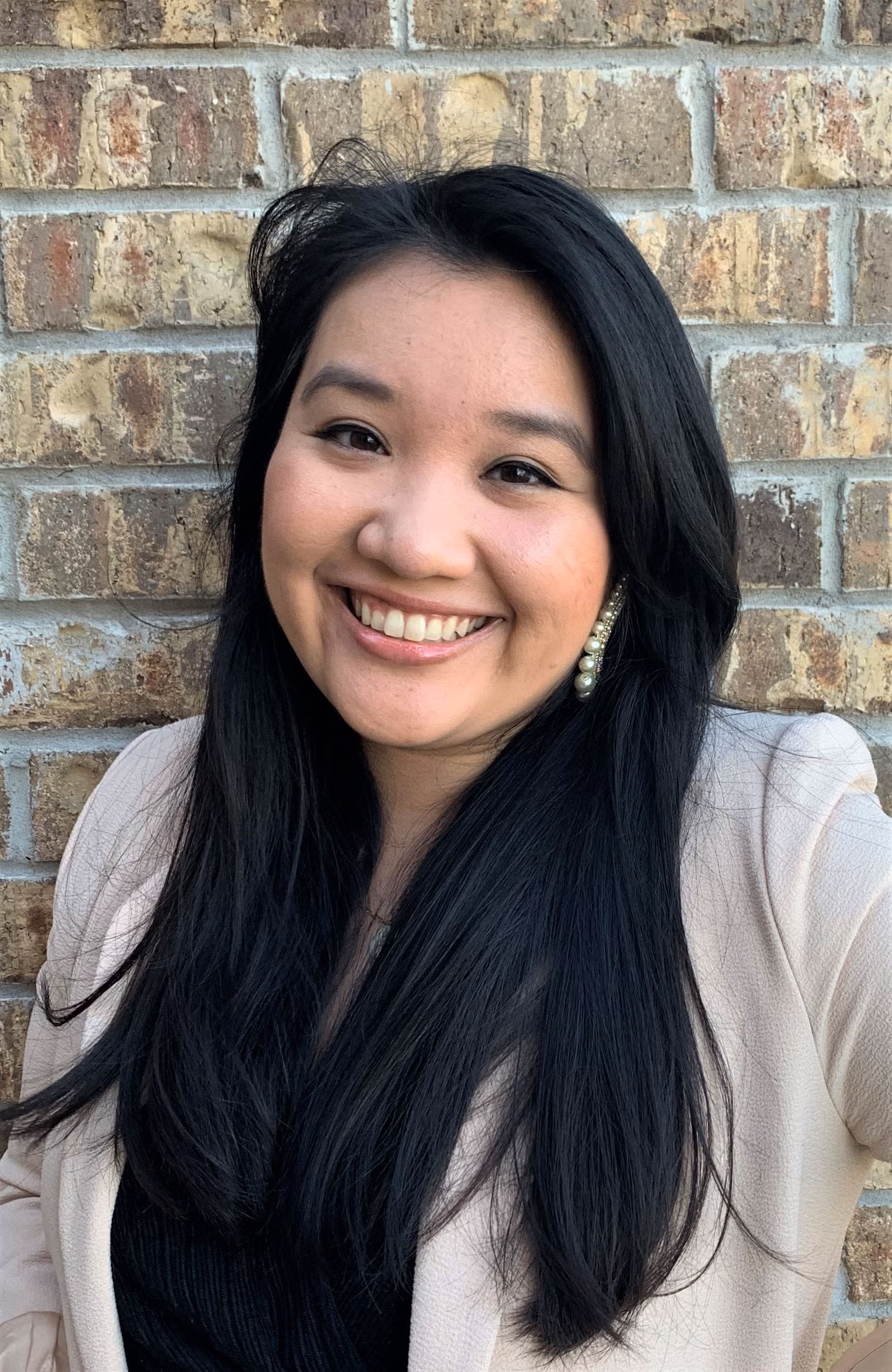Choctaw woman with long hair in front of a brick wall 