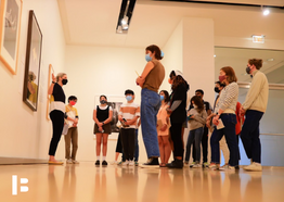 Essi pointing to an artwork, facing a group of people