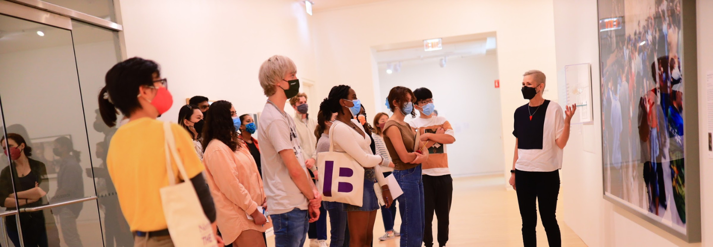 Essi pointing to an artwork, facing a group of people