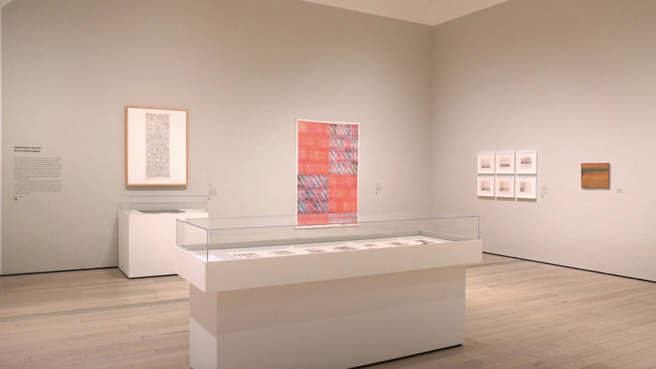 image of glass case in museum gallery space with art on walls