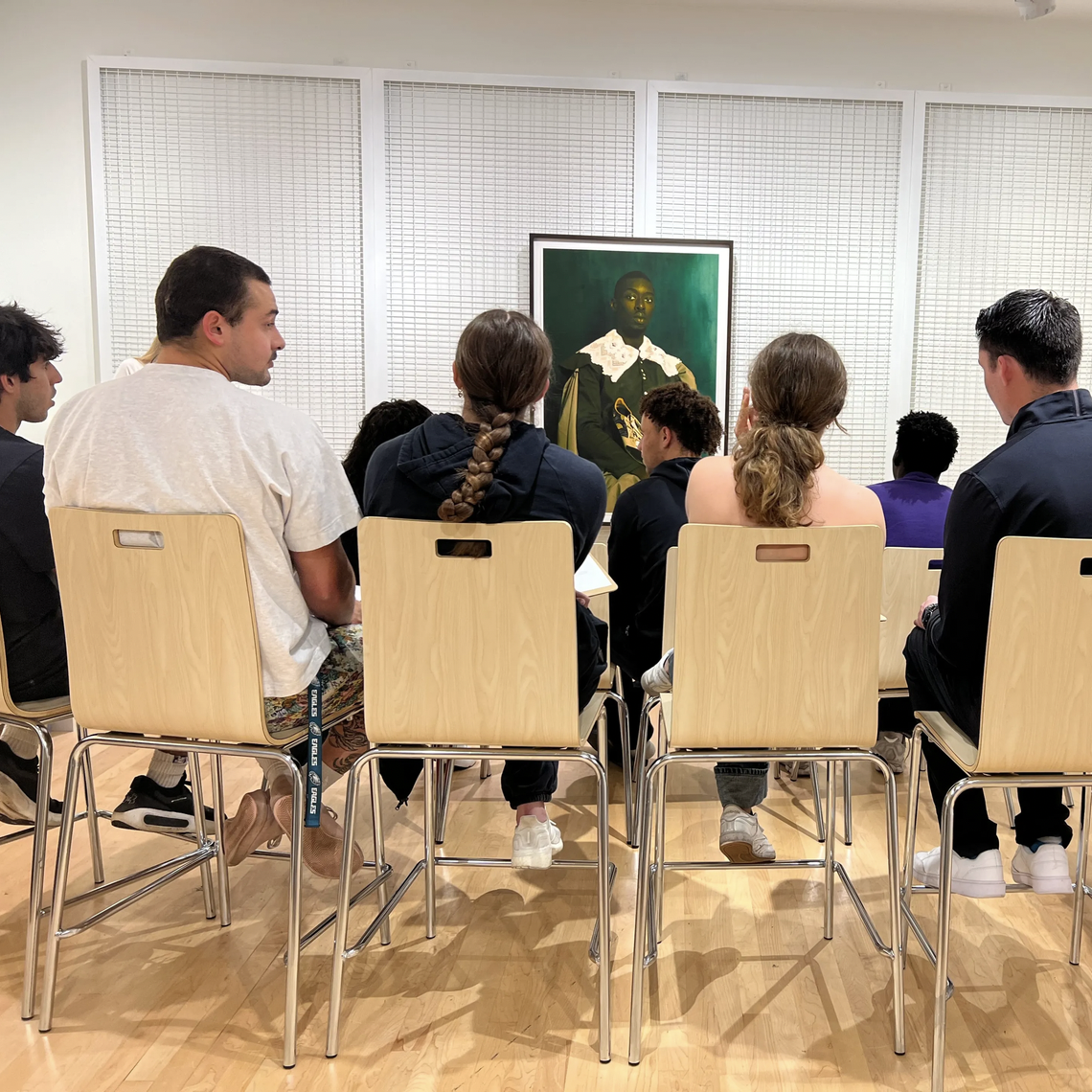 people sit in chairs in front of work on view in Block classroom